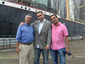 Photo: 3 members of The Forum Group staff near a boat.