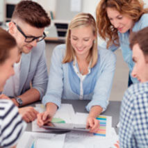 image: people working together while looking at papers