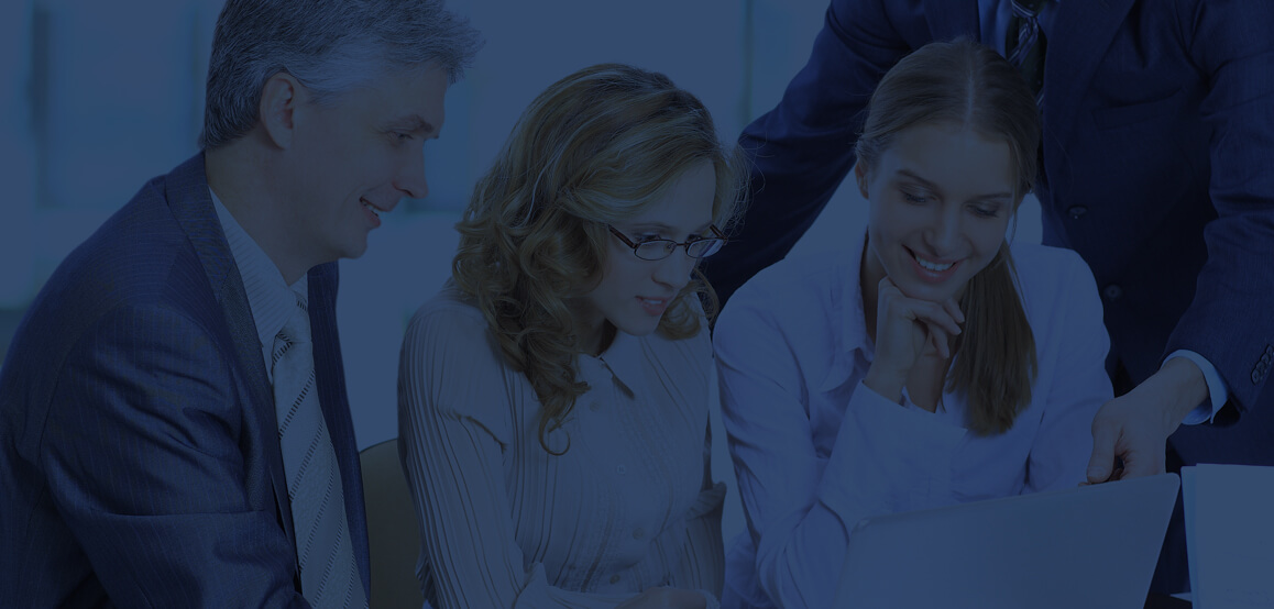 Photo: 4 employees looking at one laptop